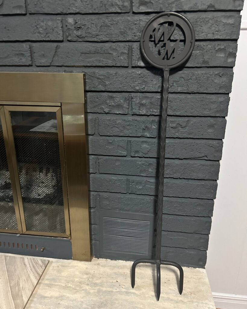 Custom handcrafted fire poker featuring precision laser-cut lettering on the handle, durable forged steel construction, and a smooth black finish—designed for both functional fire tending and personalized outdoor décor.
