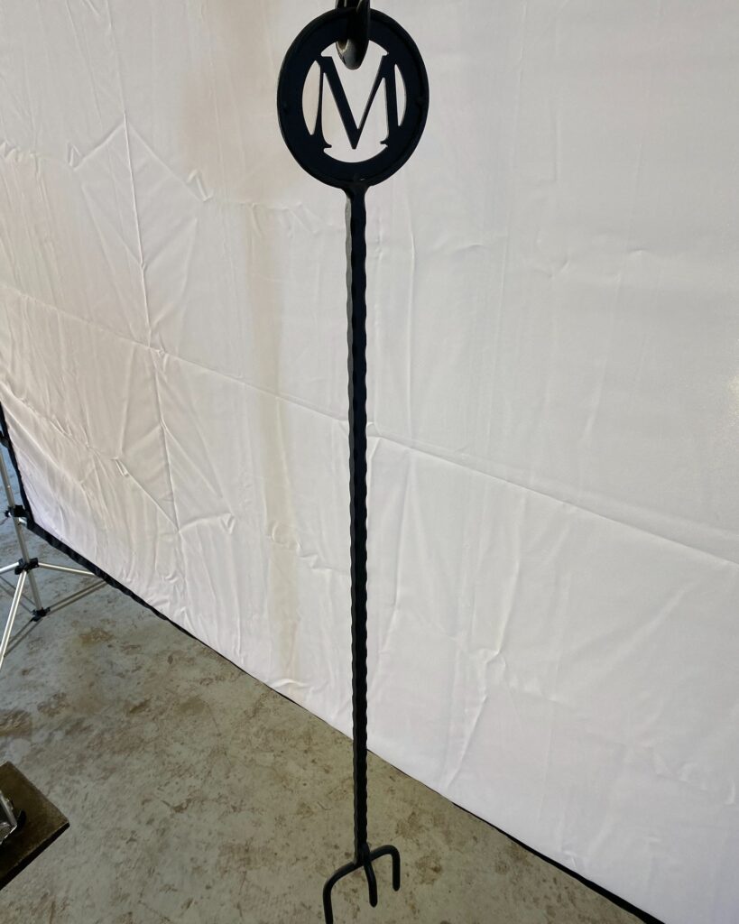 Custom handcrafted fire poker featuring precision laser-cut lettering on the handle, durable forged steel construction, and a smooth black finish—designed for both functional fire tending and personalized outdoor décor.