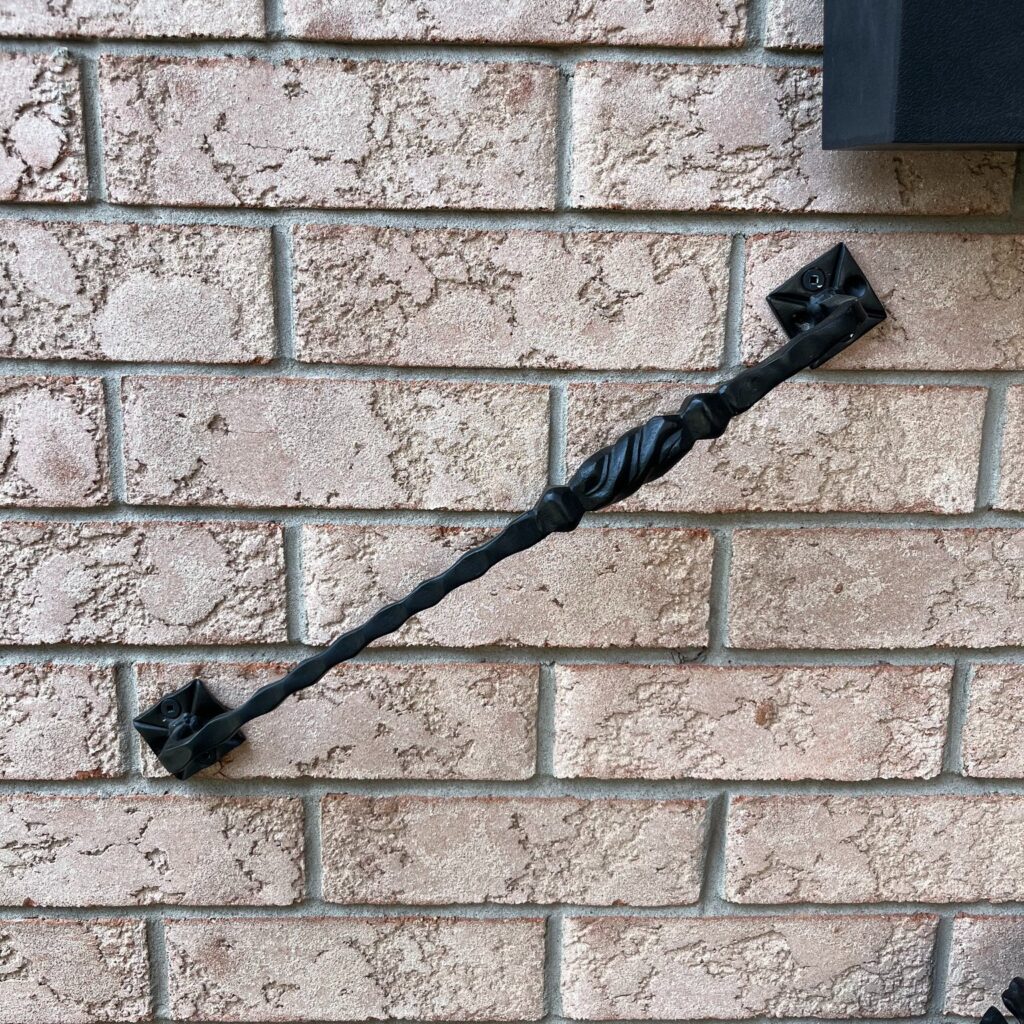 Custom fabricated iron grab bar for front porch or entrance, securely attached to a brick wall, crafted by Dream Ironwork with durable construction, precision welding, and modern design for safety and accessibility.