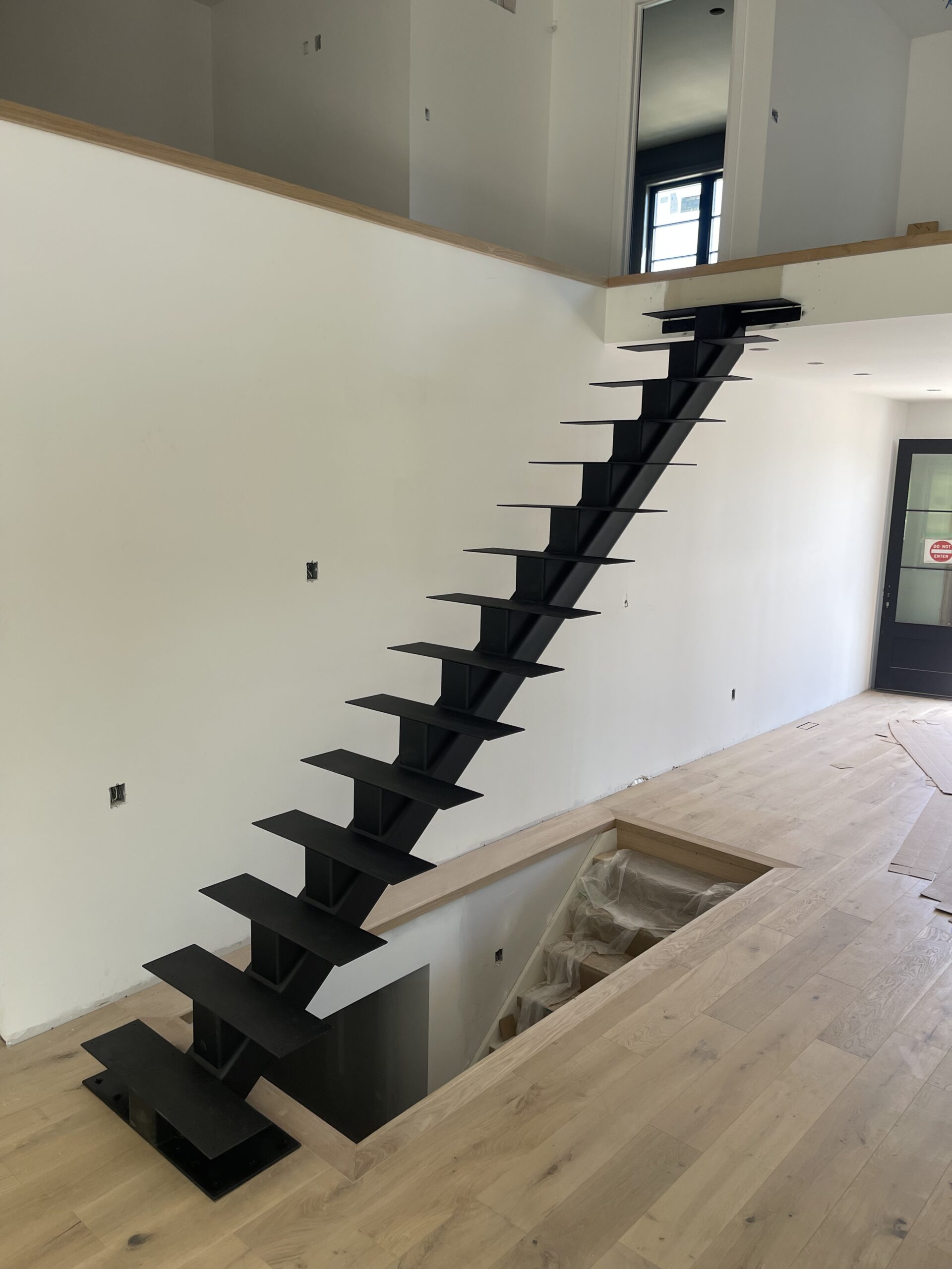 Modern floating staircase with black metal steps in a minimalist interior.