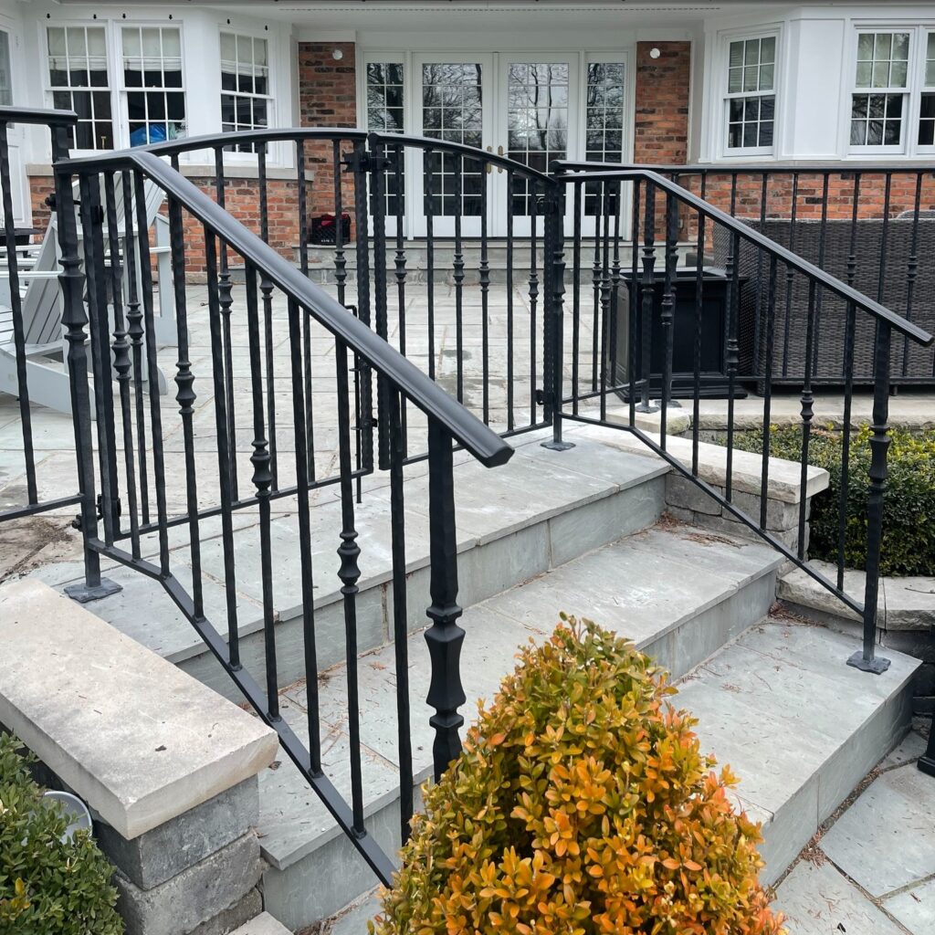 Custom fabricated wrought iron gate by Dream Ironwork featuring decorative hourglass pickets mounted directly onto the railings, handcrafted steel construction, and a durable powder-coated finish for strength and elegance.