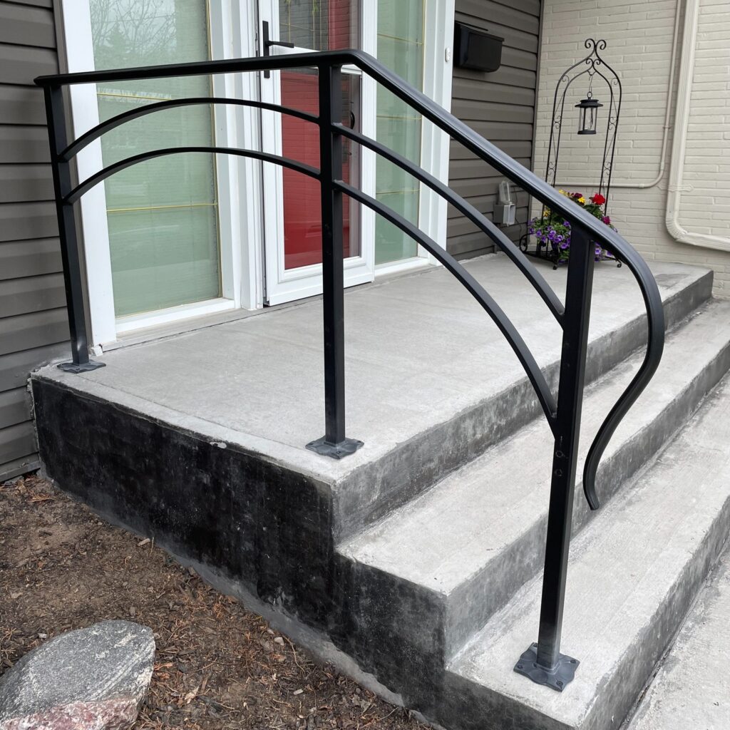 Custom fabricated iron railing with curved arch feature and extended lamb’s tongue ending by Dream Ironwork, featuring precision welding, durable construction, and elegant modern craftsmanship for residential or commercial spaces.