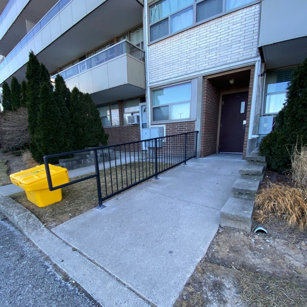 Black metal railing on concrete steps outside a commercial apartment building. Commercial railing services in Niagara. Commercial Railing contractor.