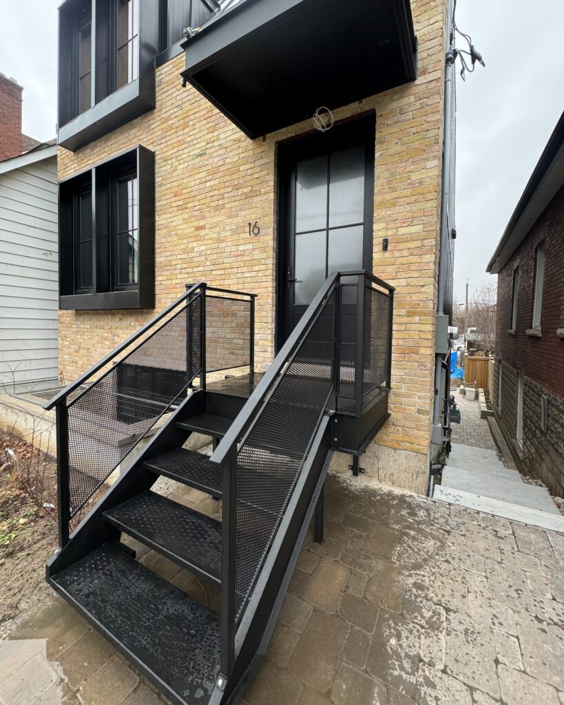 Custom fabricated metal staircase by Dream Ironwork featuring laser-cut steel treads with a diamond pattern and a modern railing with precision laser-cut mesh panels, designed for strength, durability, and contemporary architectural style.