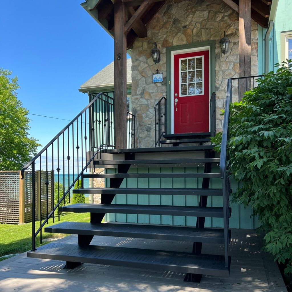 Custom fabricated transitional staircase with laser-cut steel treads and railing featuring lamb’s tongue ends and prince-knuckle pickets by Dream Ironwork, showcasing precision craftsmanship, durable construction, and a refined blend of modern and classic design.