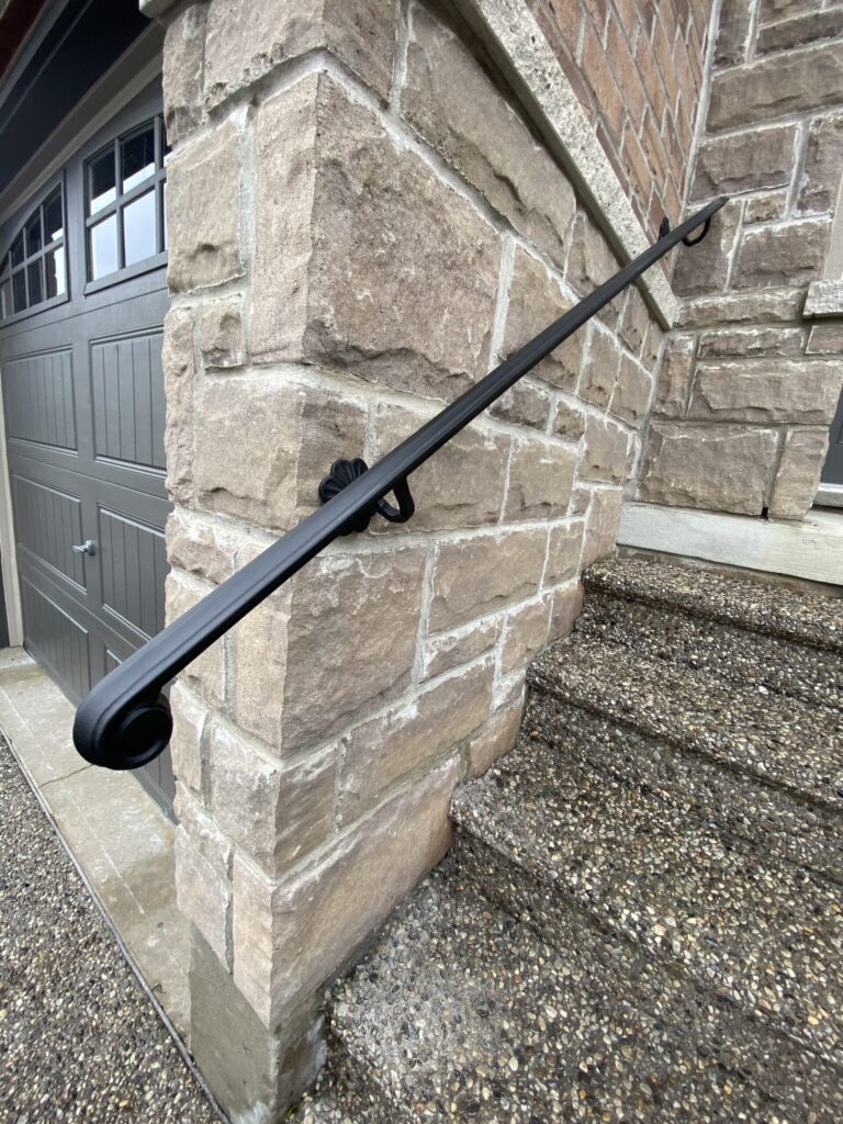 Wrought iron railing professionally installed on stone exterior wall