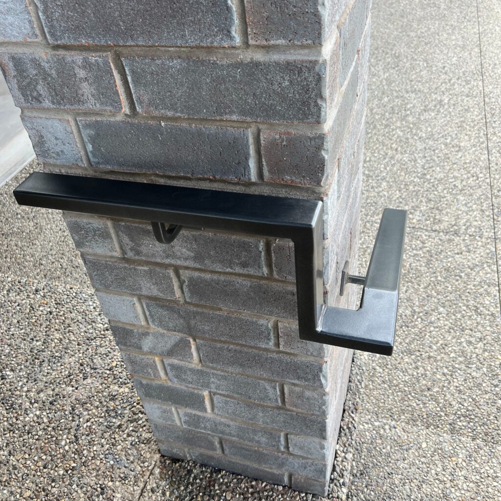 Custom fabricated wall-mounted iron handrail in gunmetal grey by Dream Ironwork, showcasing precision welding, modern design, and durable craftsmanship for residential and commercial railing installations.