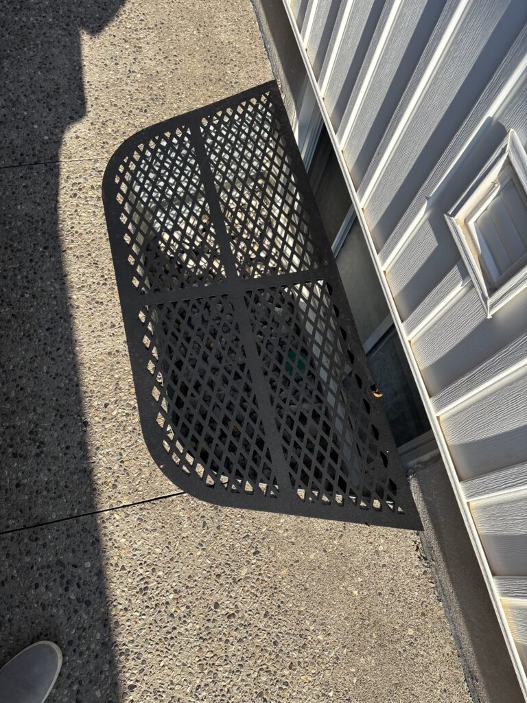 Custom steel window grate on a side entrance of a home. Custom diamond pattern grate.