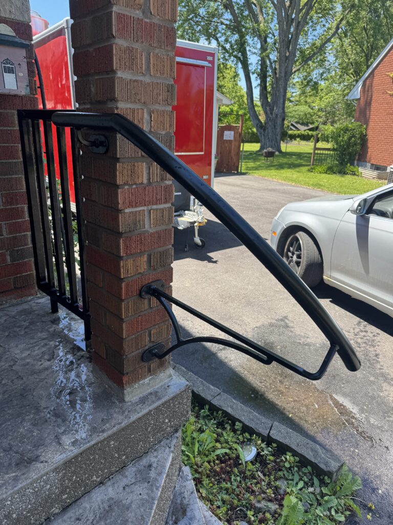 Custom fabricated wall-mounted iron handrail in gunmetal grey by Dream Ironwork, showcasing precision welding, modern design, and durable craftsmanship for residential and commercial railing installations.